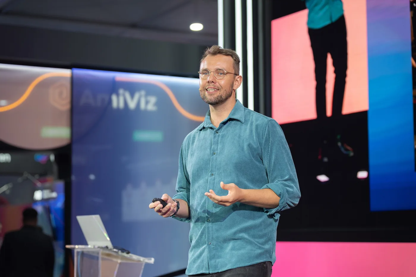 Aaron Jones speaking on stage, wearing a headset and holding a presentation clicker