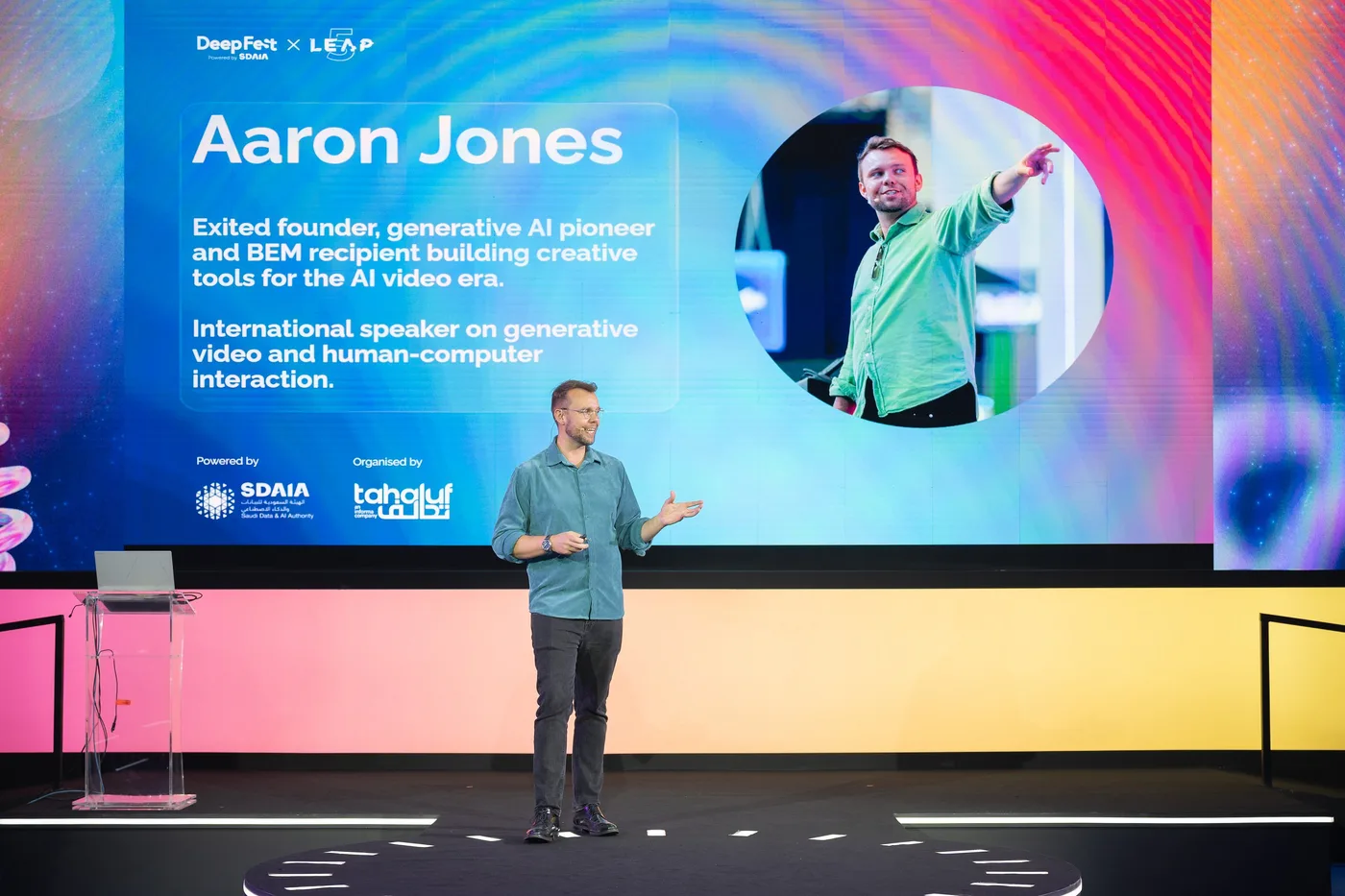 Aaron speaking in front of his introduction on the large DeepFest and LEAP screen