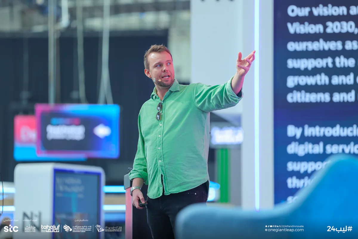 Aaron presenting at LEAP 2024 in a green shirt, gesturing towards the audience